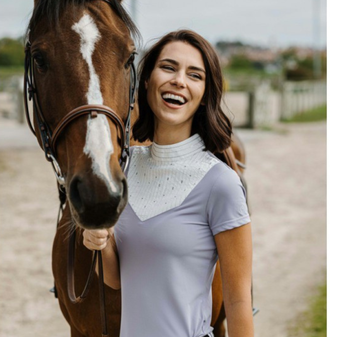 Lady with horse wearing light purple or mauve competition shirt with delicate gold trim